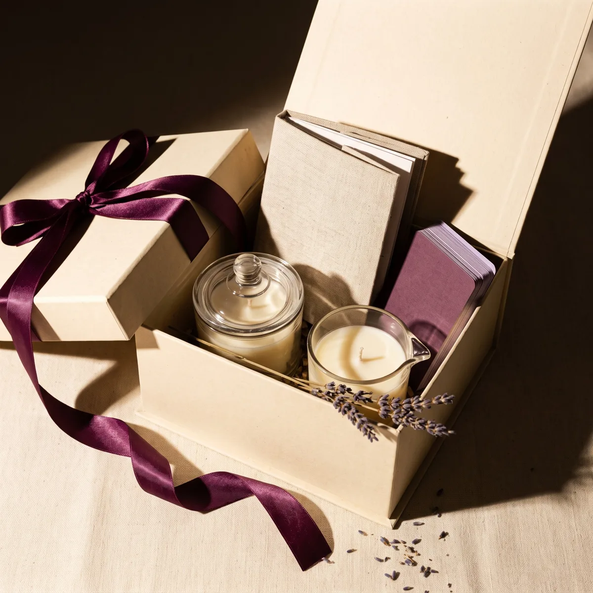 Caixa do Kit A Dois aberta, com vela aromática, vela de massagem, manual e baralho, à luz de vela